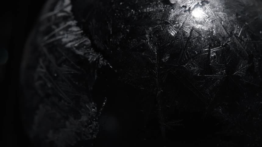 A dark object with ridges reflects light