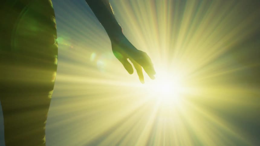 A person moving their hands as yellow laser light shines on it