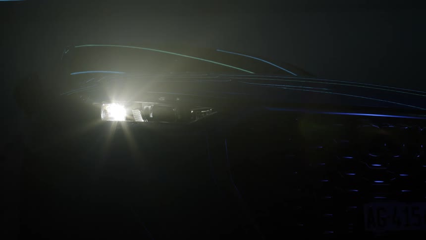 The headlight and directional signal of a car flash and glow at night