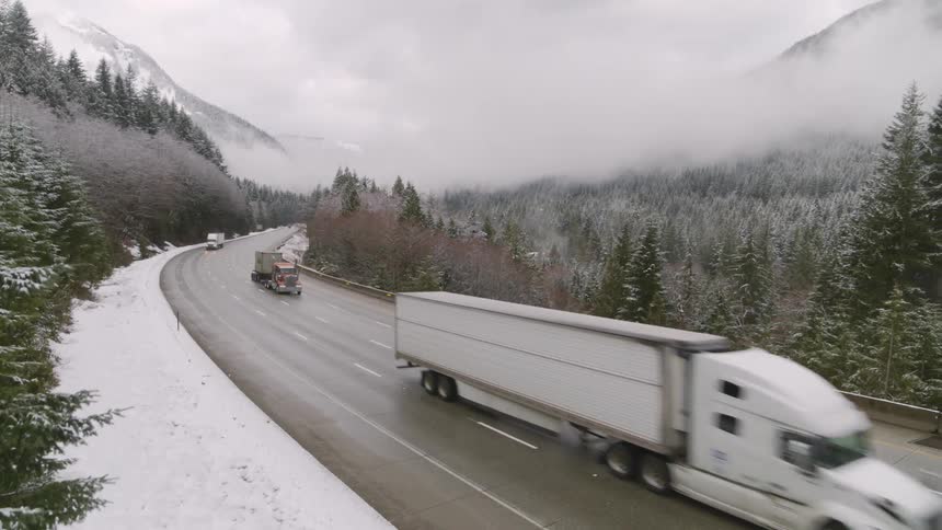 Ascending next to a wintery mountain pass highway as truckers haul cargo uphill