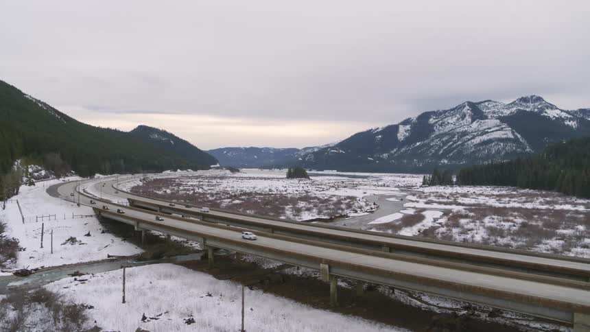 Winter travel along a six lane freeway in a valley between tall mountains