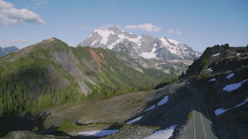A car travels up a hairpin curve along a steep mountain road