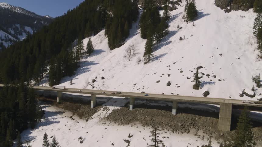 Vehicles driving on an elevated highway above a mountainside avalanche chute