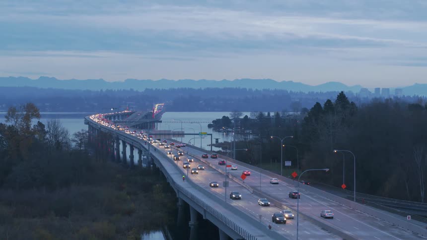 Commuters on bikes and in cars travel along a bridge during morning rush hour