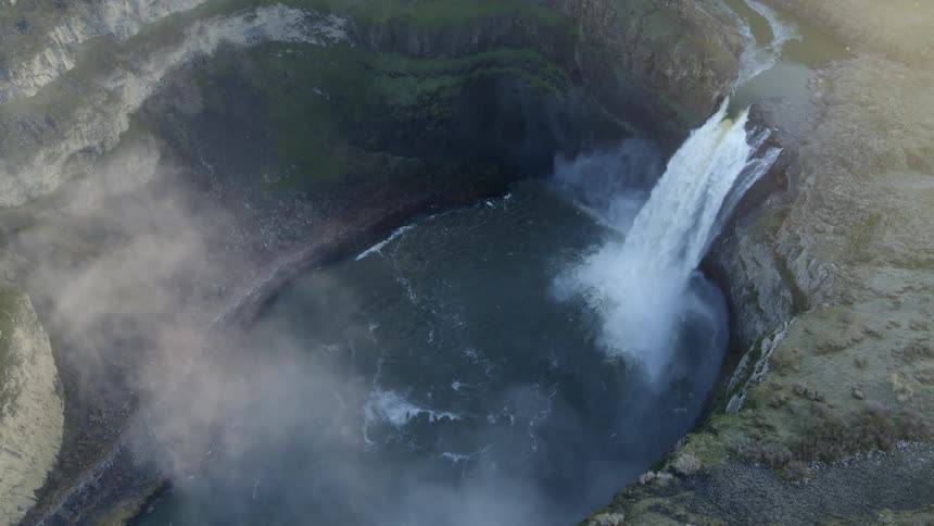 Subtle orbit over a canyon waterfall pouring into a large plunge pool below