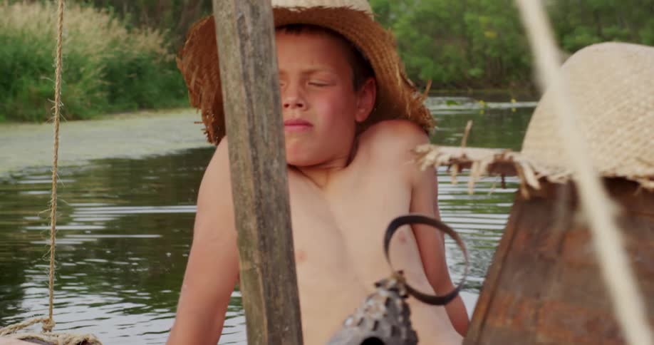 Two boys float on a river on a raft they made on a hot summer day