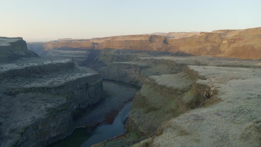 Skimming along rugged cliffs above a deep river canyon at dawn