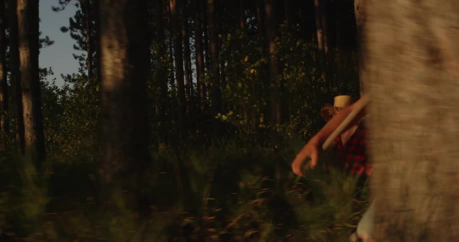 A group of kids walk through the woods while toting tools