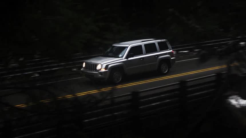 A vehicle drives down a road in the winter