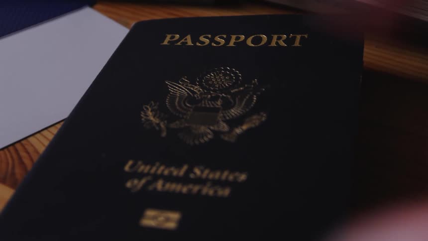 Close up of a man hand picking up a passport from a table