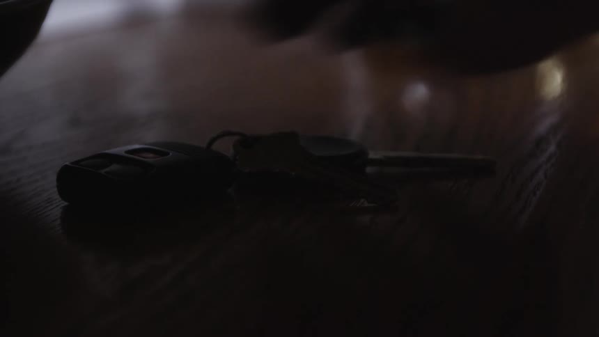 A man grabs his keys off a table