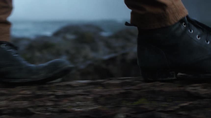 A persons feet wearing boots walking on a log