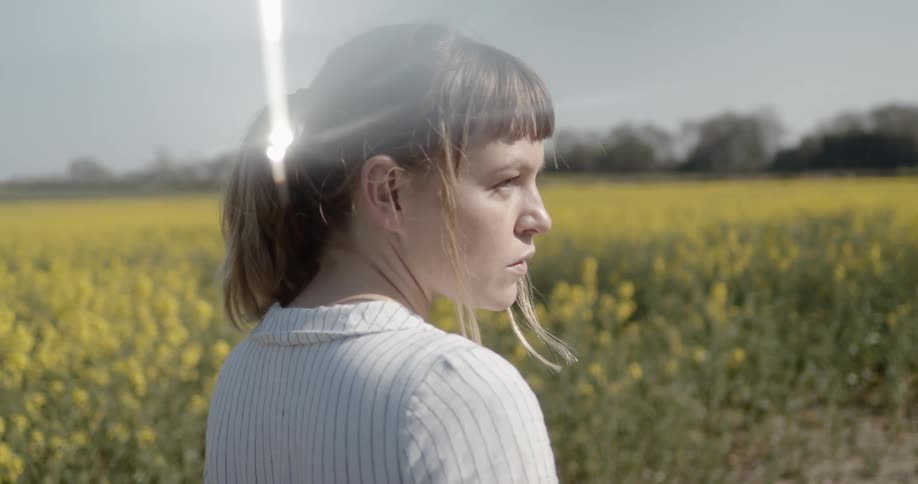 A woman stands in a field full of yellow flowers