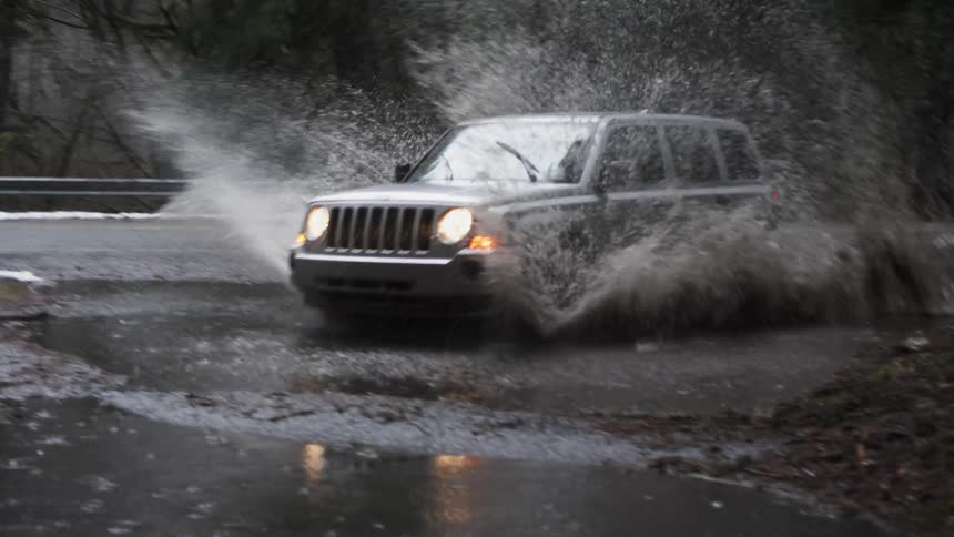 A car is driving through a puddle of water