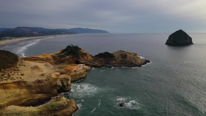 An island sits off the coast of a rocky promontory