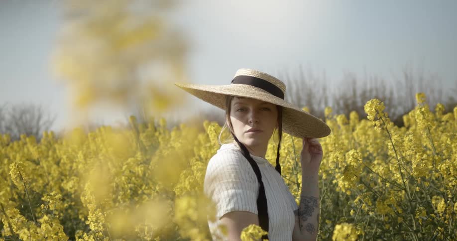 A woman stands in a field of flowers and looks around