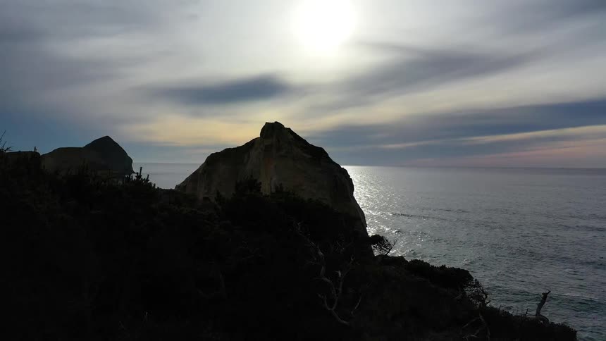 A cliff on the shore with the water extending to the horizon