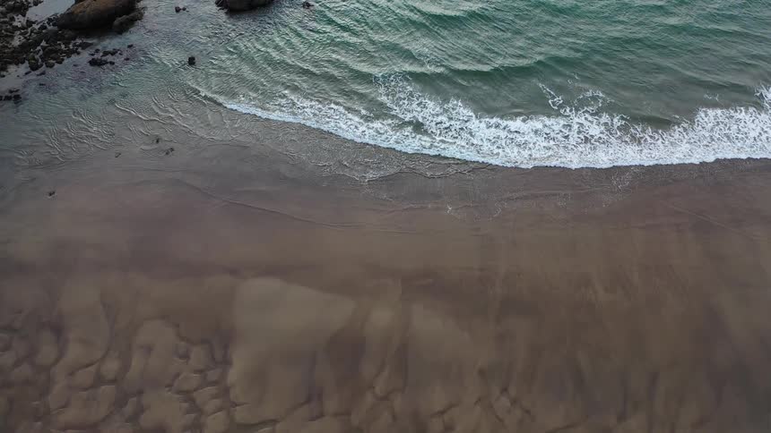 Ocean waves roll into shore near the rocks