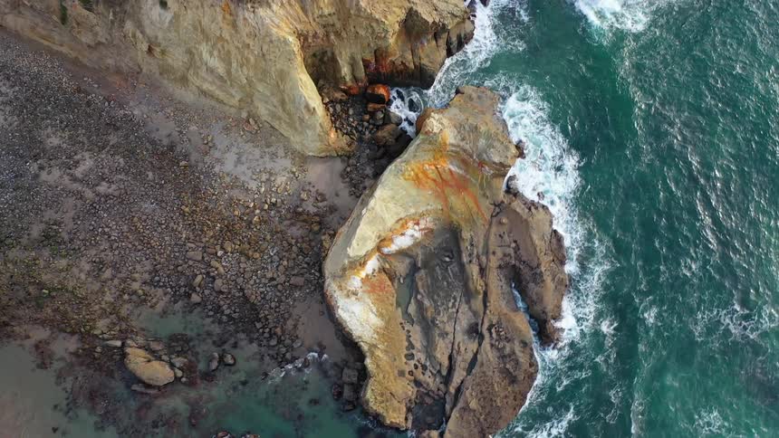 Birds eye view of rugged shoreline cliffs and breaking waves