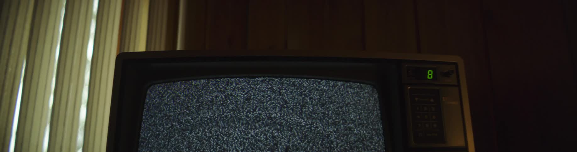 A television in a darkened room cycles through channels of static