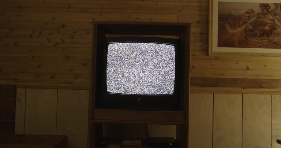 A television in a wooden stand plays static