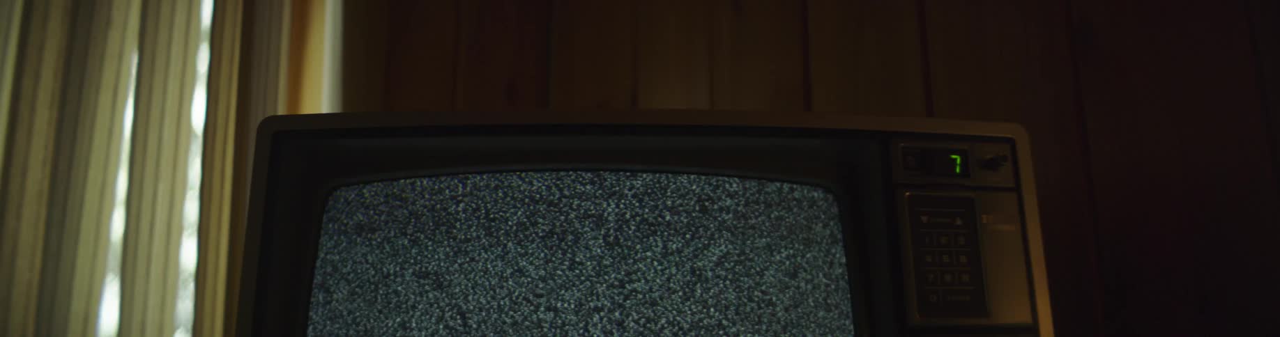 Vintage television set shows static on the screen in a dimly lit room