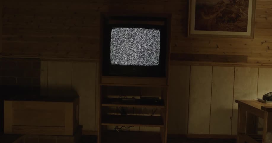Vintage television set on dimly lit living room shows static in screen