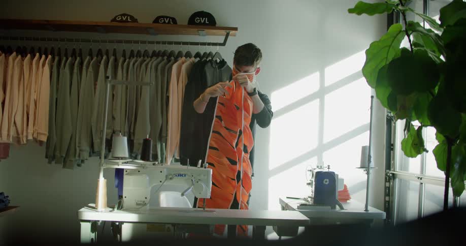 A white male teenager stands in a room and examines a row of face masks