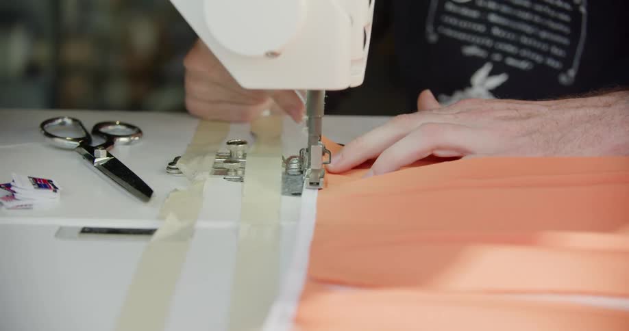 A white woman uses a sewing machine to work on a piece of fabric