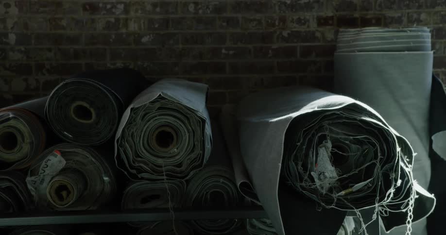 Rolls of fabric piled up against a brick wall