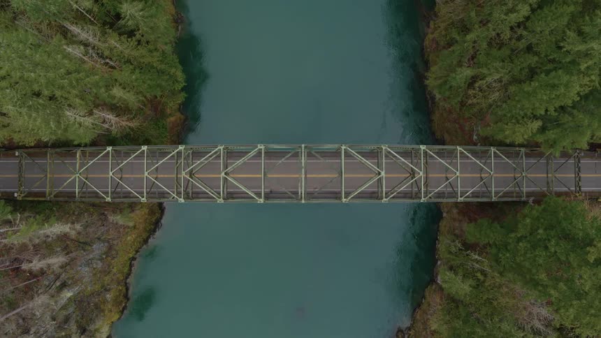 A bridge spanning a river that connects to sides of a forest