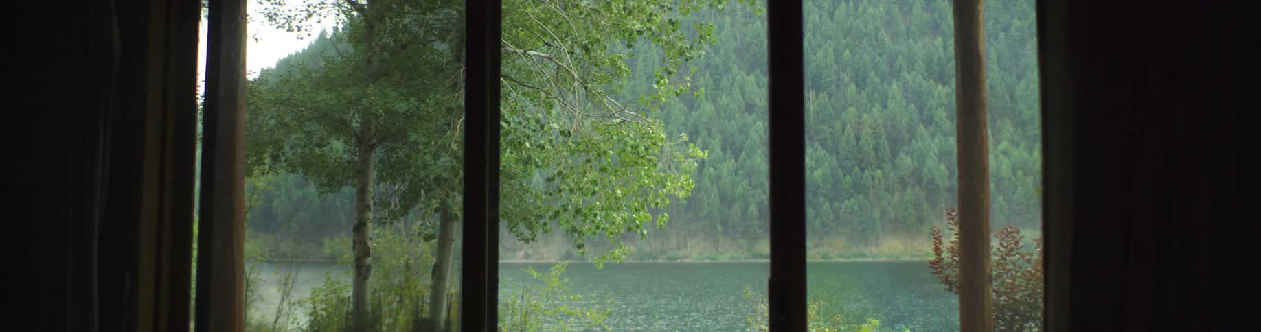 A house has a view of a lake and a mountain covered in a forest