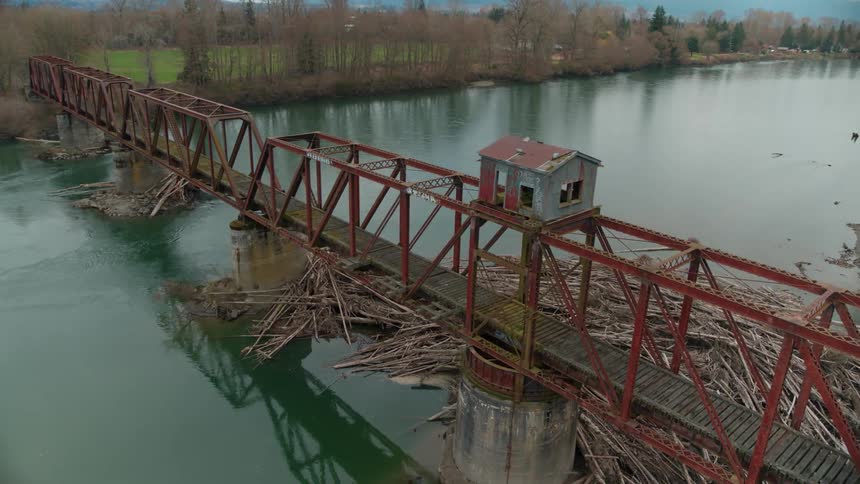 Logs in a river jammed up underneath an old pedestrian bridge