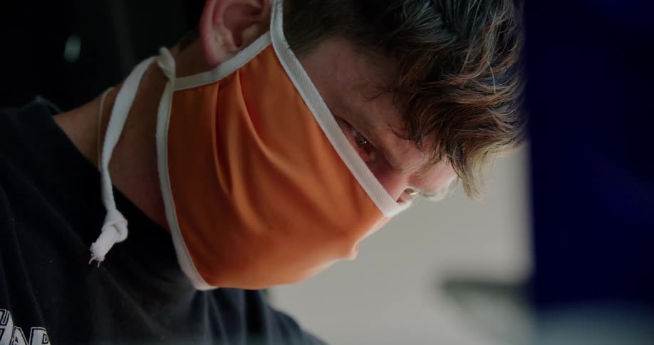 Man wearing orange cloth face mask looking down