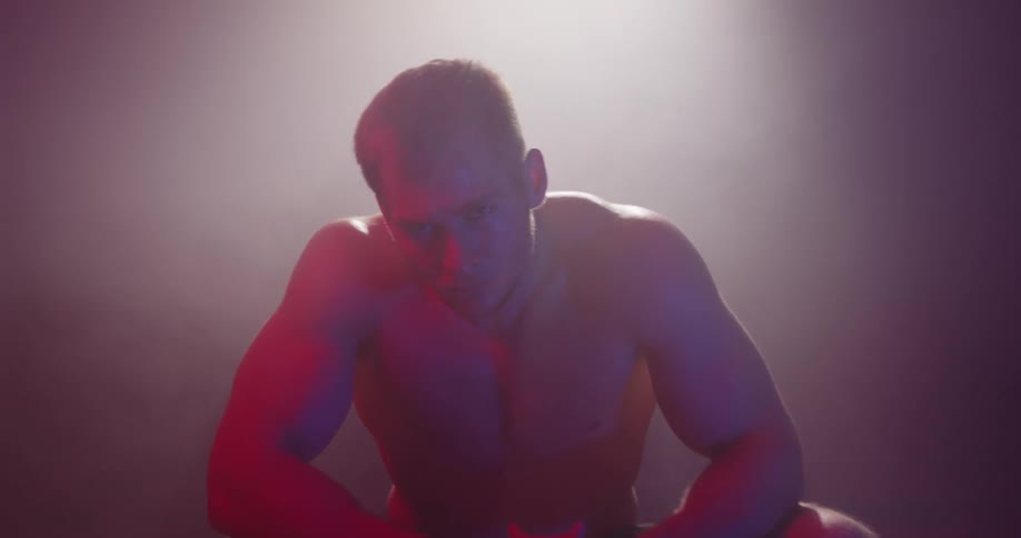A young white man in a crouch turns his face upward