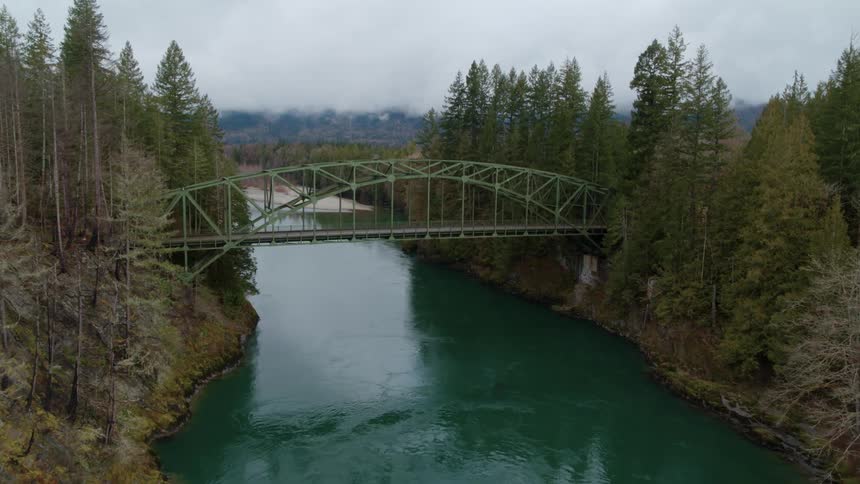 A bridge spanning a bluegreen river splitting a forest