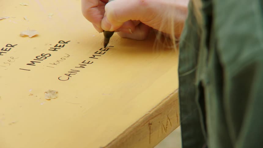 A person writing on a table with a marker