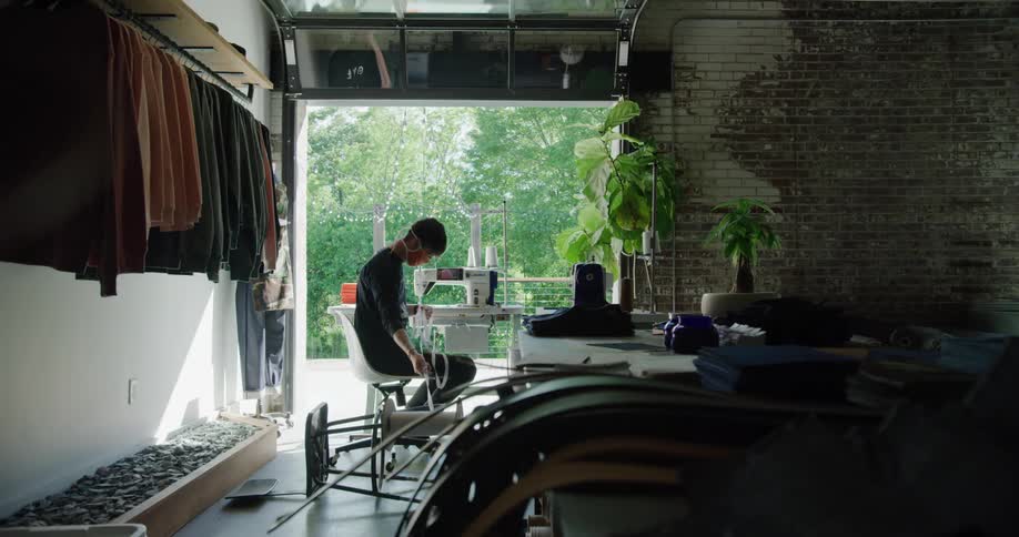 A man in a business pulls up ribbon to sew with