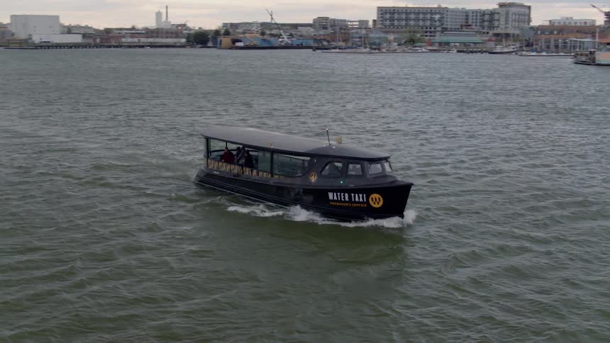A water taxi boat moves across a harbor