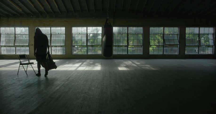 A person carrying something walks across an empty window filled room