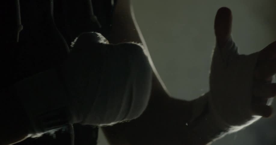 A person is wrapping their hands in a dark room