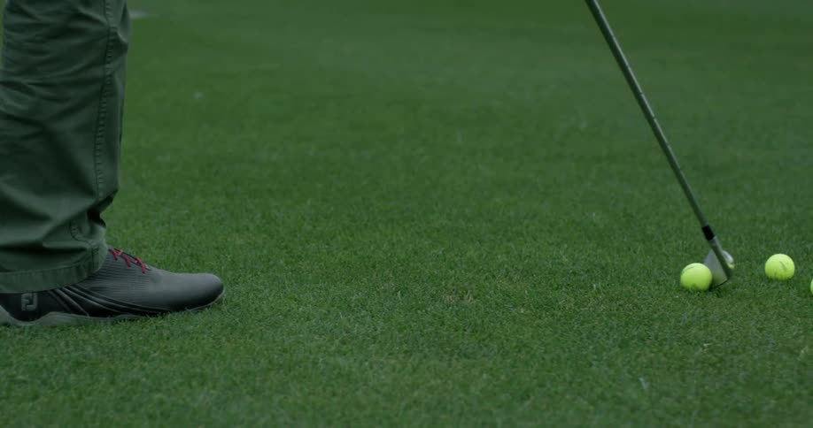 A man is walking across grass carrying a golf club
