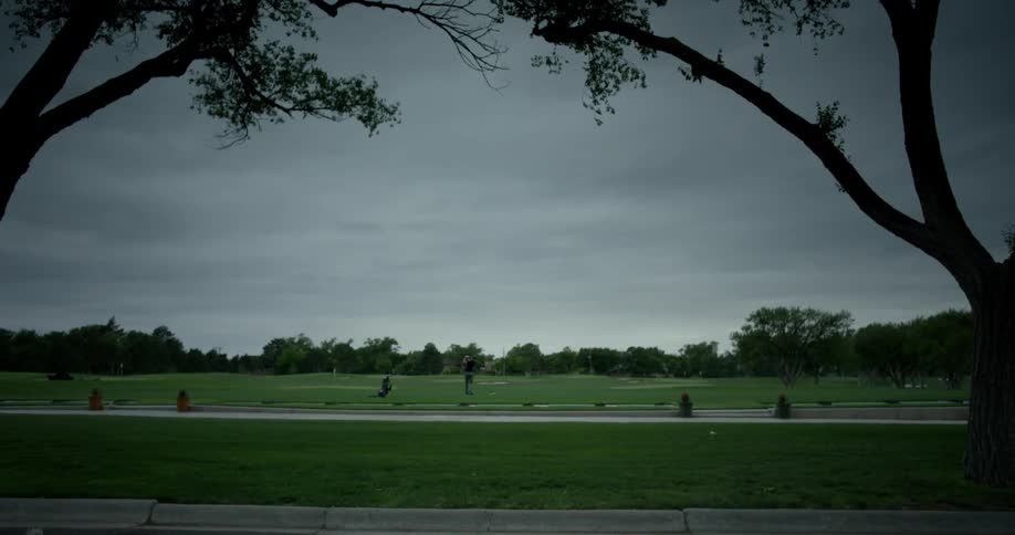 A golfer swinging his club on a rainy day