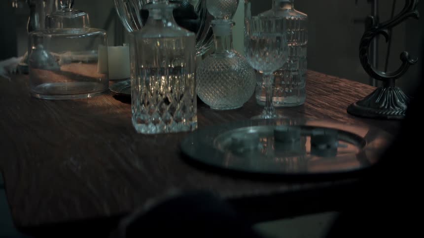 A plate and various decanters and glass bottles litter a dining table
