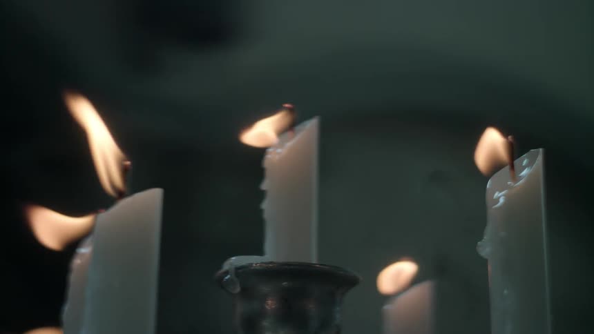 Several white candles burning on a candelabra
