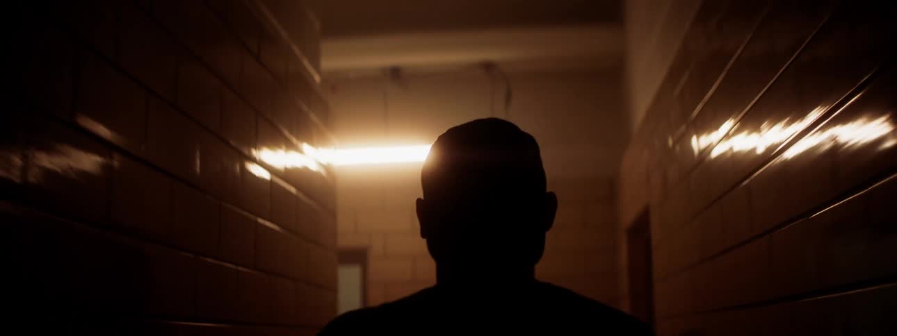 Man walks out of dim hallway onto bright basketball court