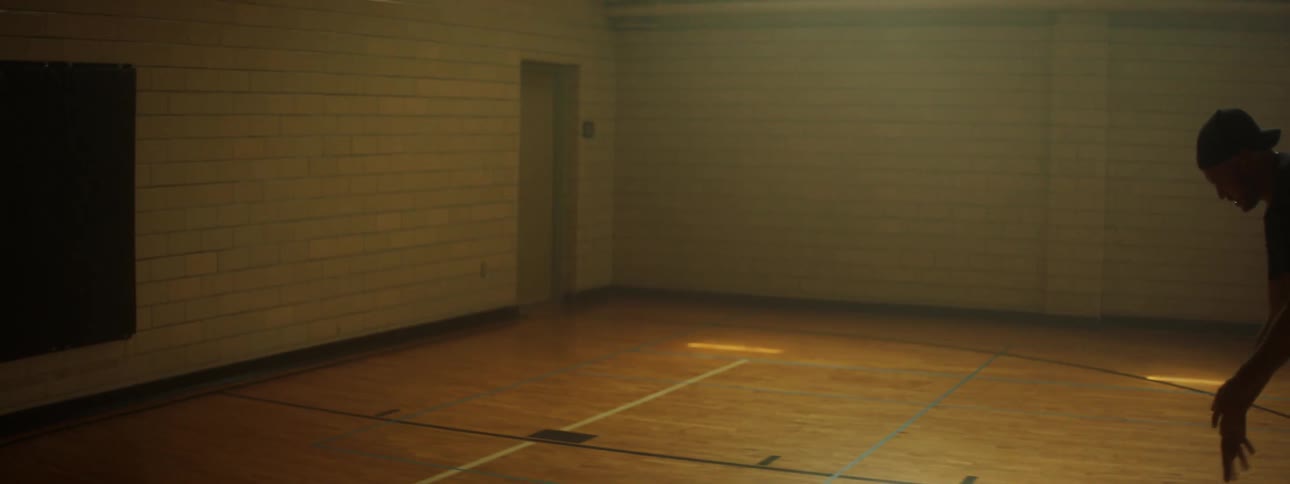 A white man shoots hoops in a gym