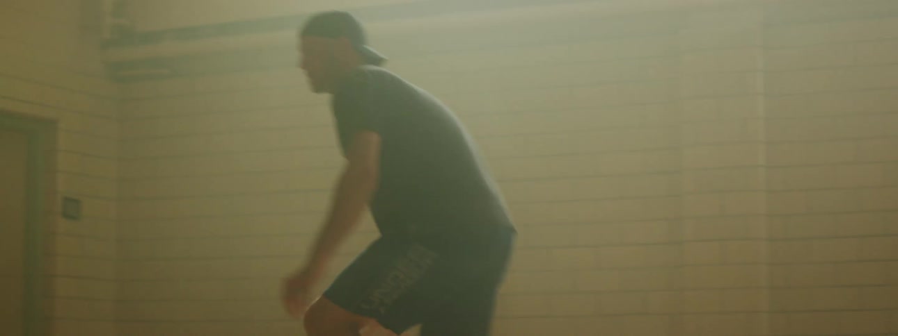 A white man plays basketball alone in a gym