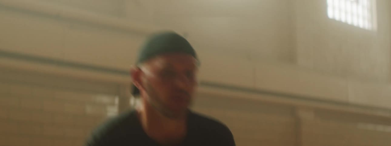 Man wearing reversed baseball cap dribbles then takes a shot