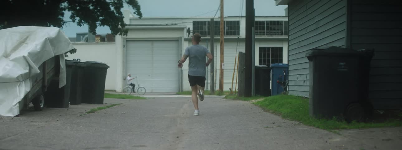 A man jogs through a suburban garage alley